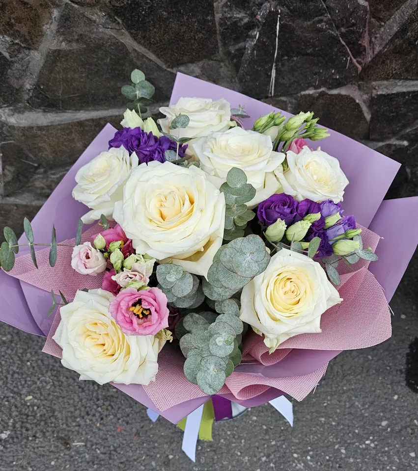 Buchet cu trandafiri albi, lisianthus mov și eucalipt, în hârtie lila