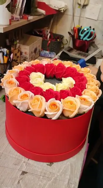 Cutie roșie cu trandafiri așezați în formă de inimă